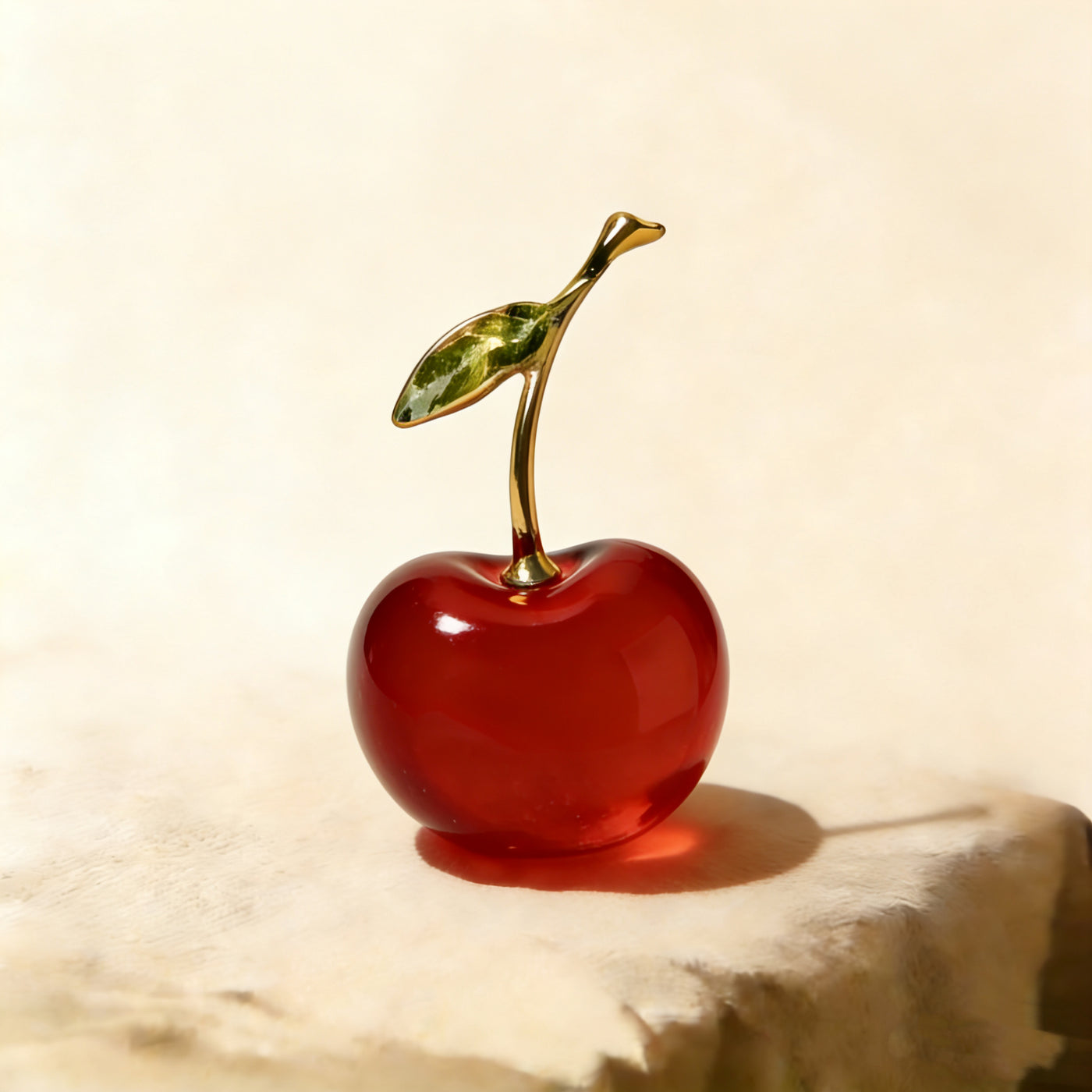 Close-up of the gold-tone stem and green glass leaf on the crystal cherry sculpture
