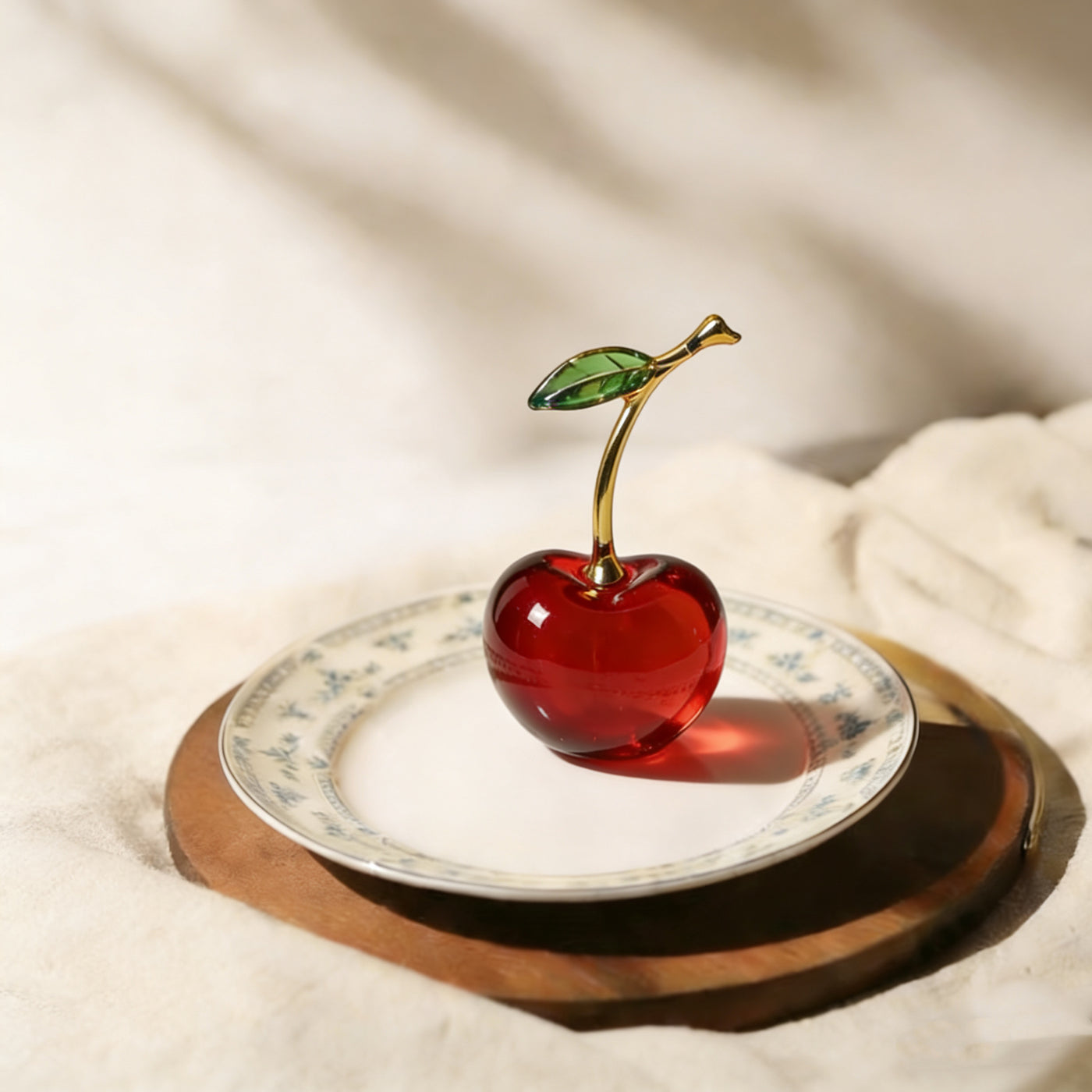 Red crystal glass cherry figurine with gold-tone stem and green glass leaf