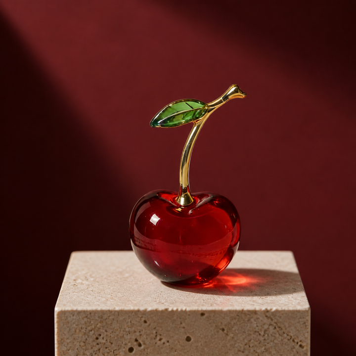 Red crystal glass cherry figurine on an ivory travertine plinth