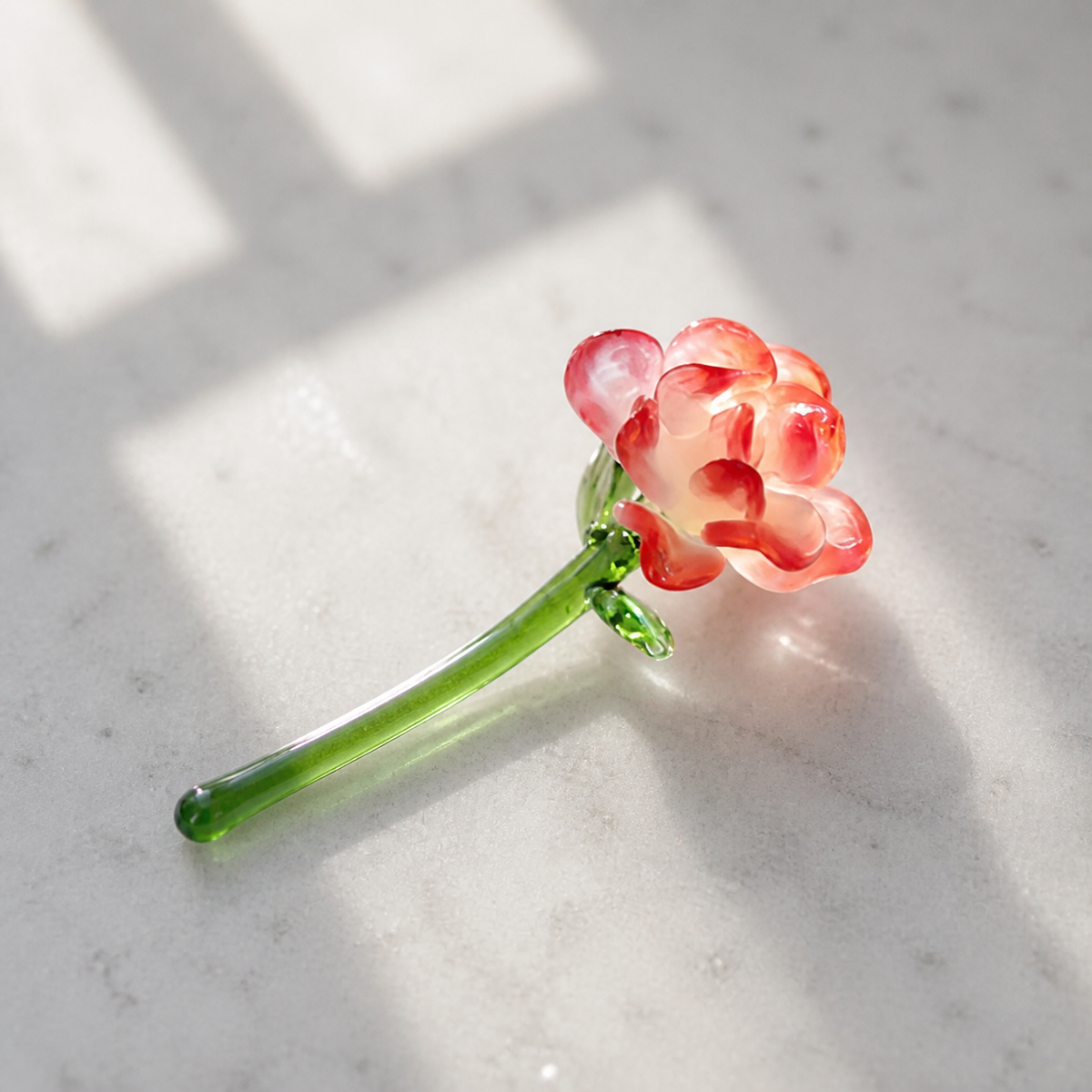 Red handmade glass carnation stem detail on pale stone